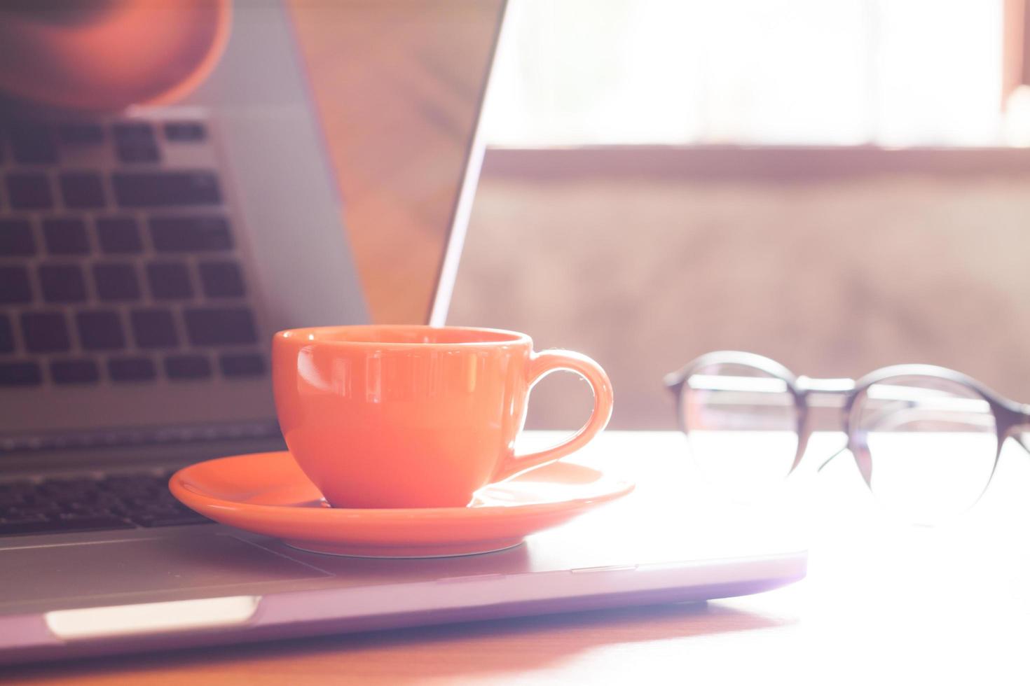 tazza di caffè arancione su un computer portatile con gli occhiali foto