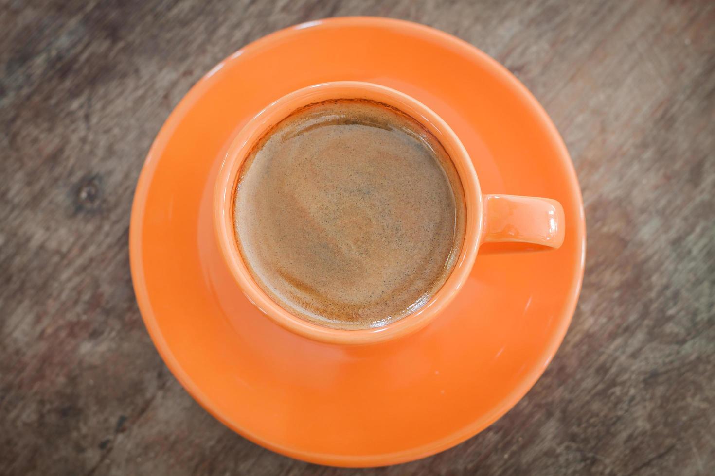 vista dall'alto di una tazza di caffè arancione e piattino foto