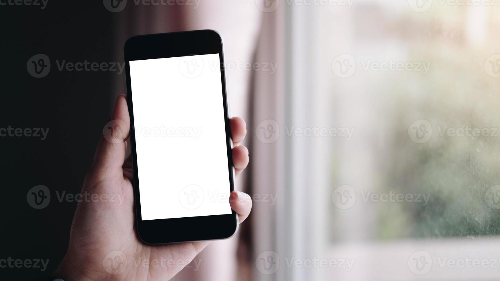 primo piano della mano di una donna utilizzando uno smart phone con schermo vuoto a casa foto