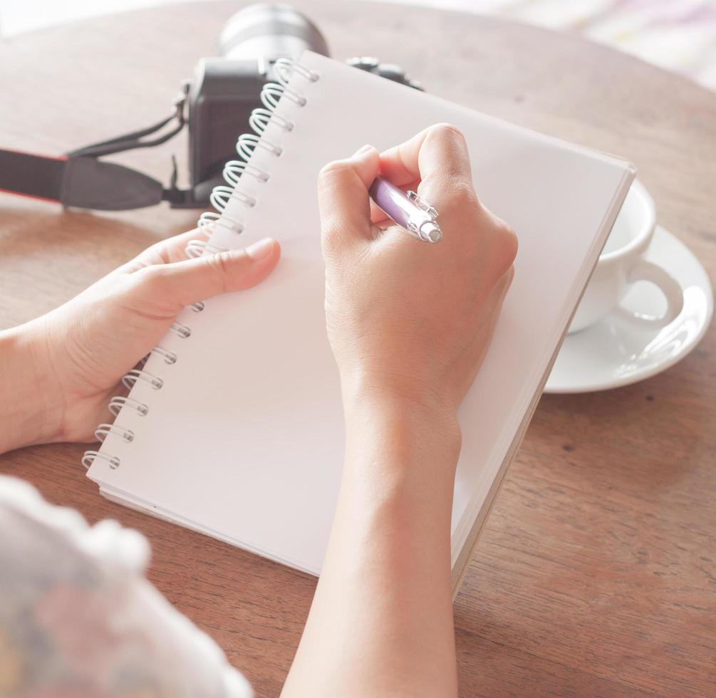 primo piano di una donna che scrive in un taccuino foto