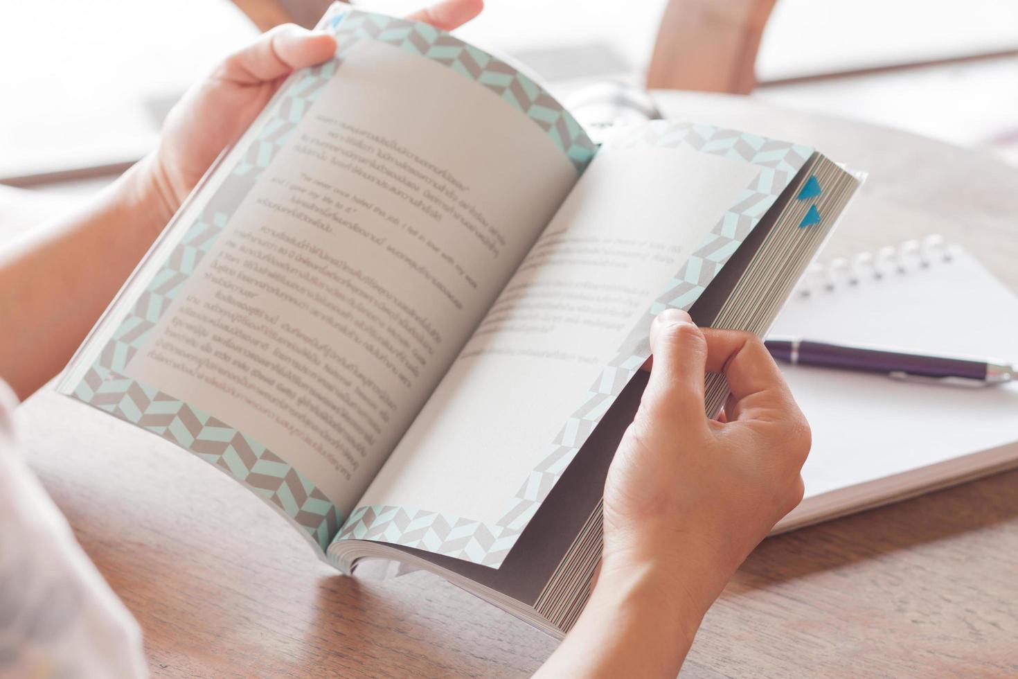 primo piano delle mani che tengono un libro in un caffè foto