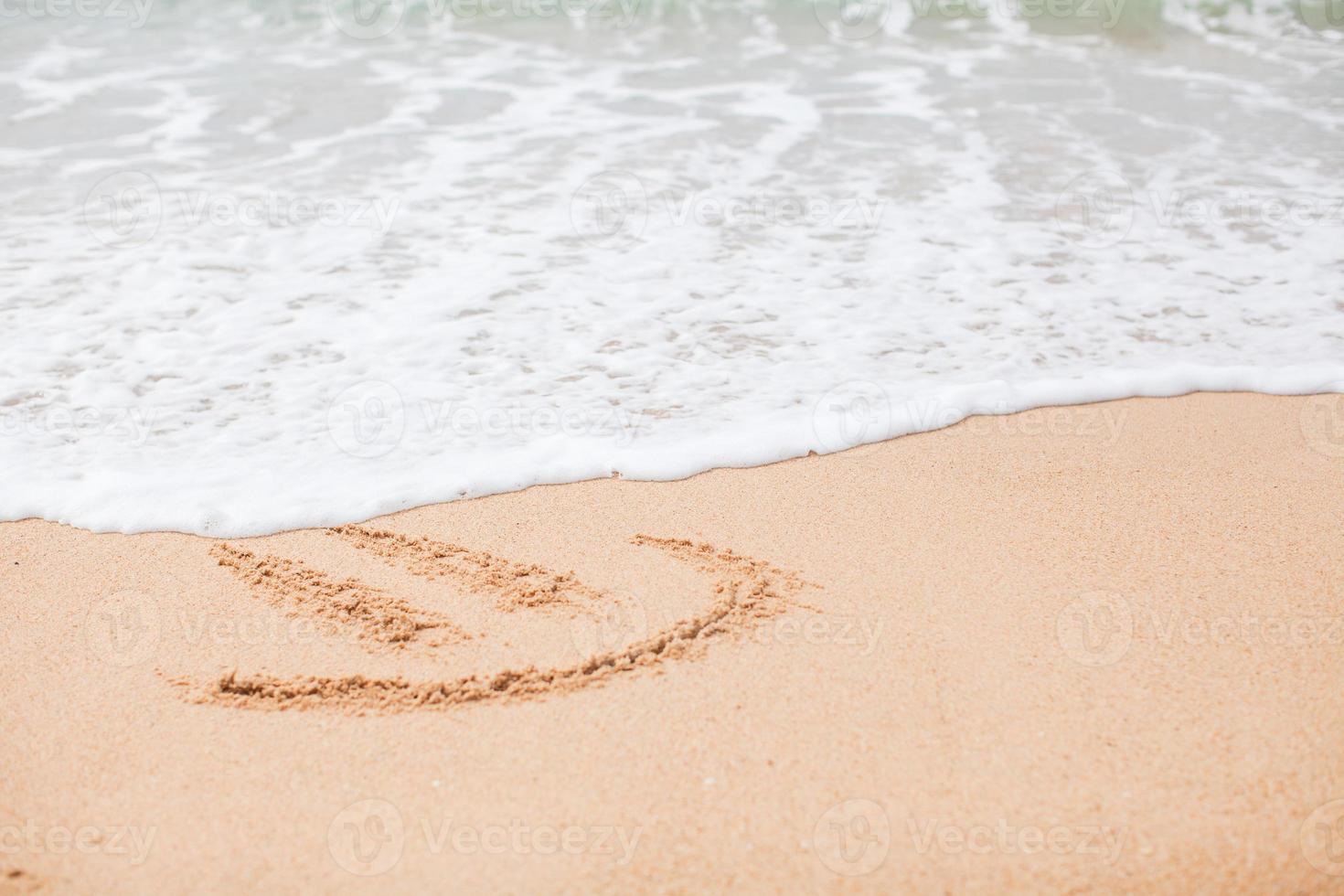 contento Sorridi disegno su il sabbia a tropicale spiaggia foto