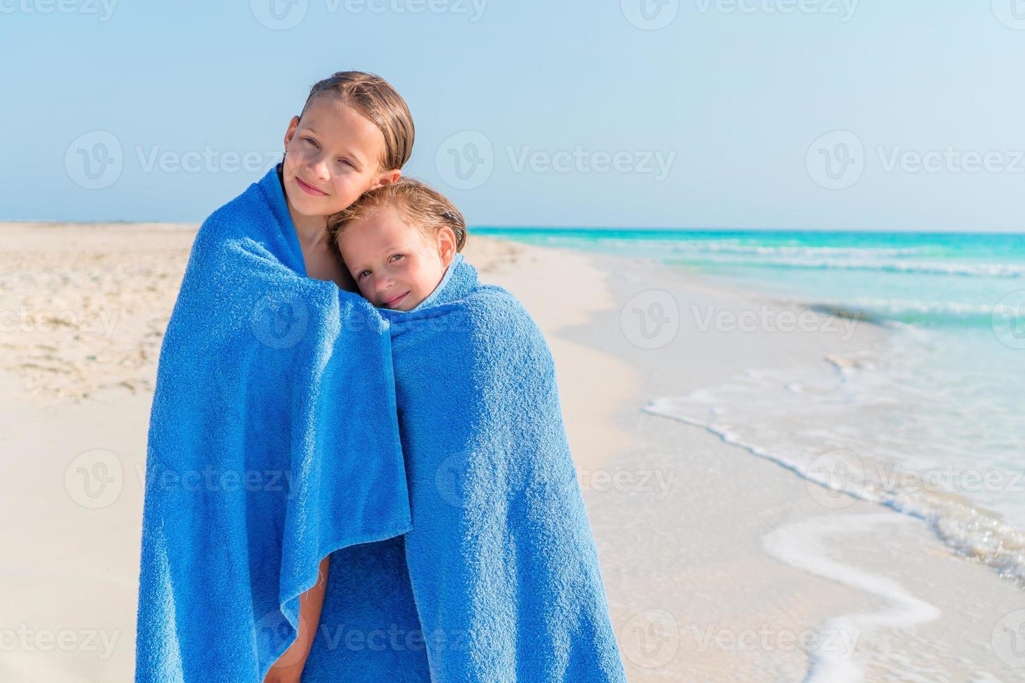 adorabile poco ragazze insieme avvolto nel asciugamano a tropicale spiaggia foto
