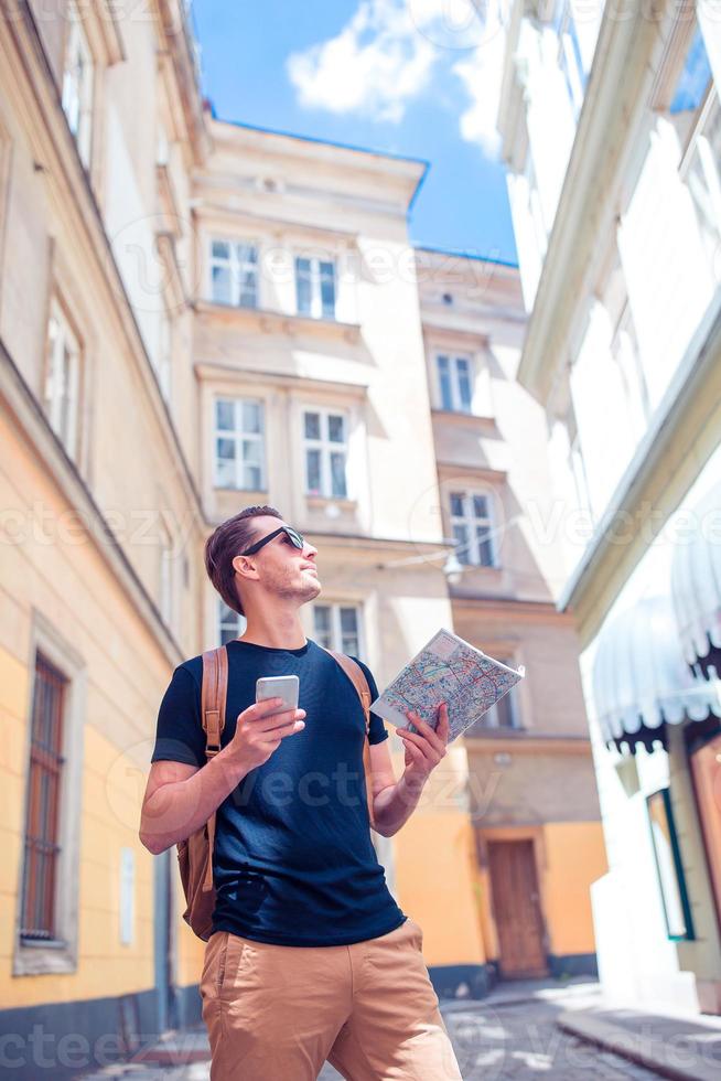 uomo turista con un' città carta geografica e zaino nel Europa strada. caucasico ragazzo guardare con carta geografica di europeo città. foto