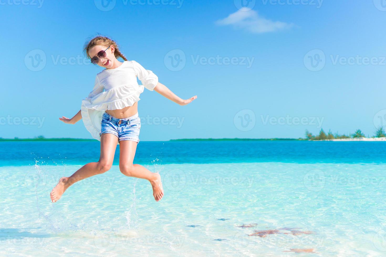 divertente poco ragazza a spiaggia avendo un' lotto di divertimento foto