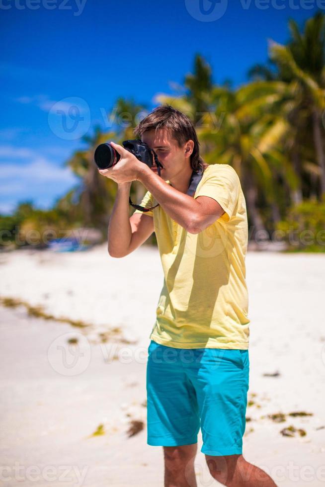 giovane che scatta foto su una spiaggia tropicale
