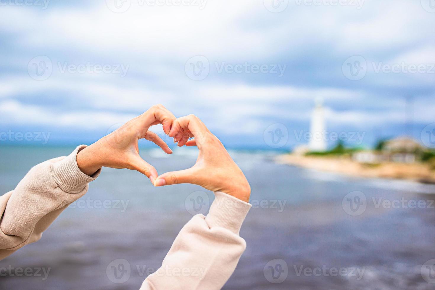 femmina mani nel il modulo di cuore contro il faro foto