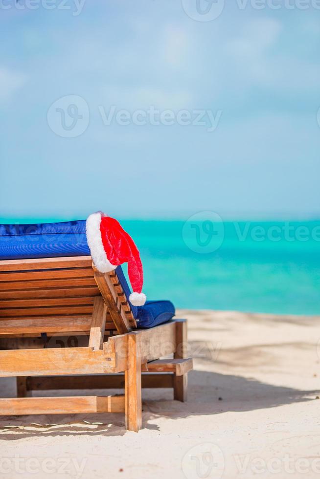 Santa Claus cappello su spiaggia lettino con turchese mare acqua e bianca sabbia. Natale vacanza concetto foto