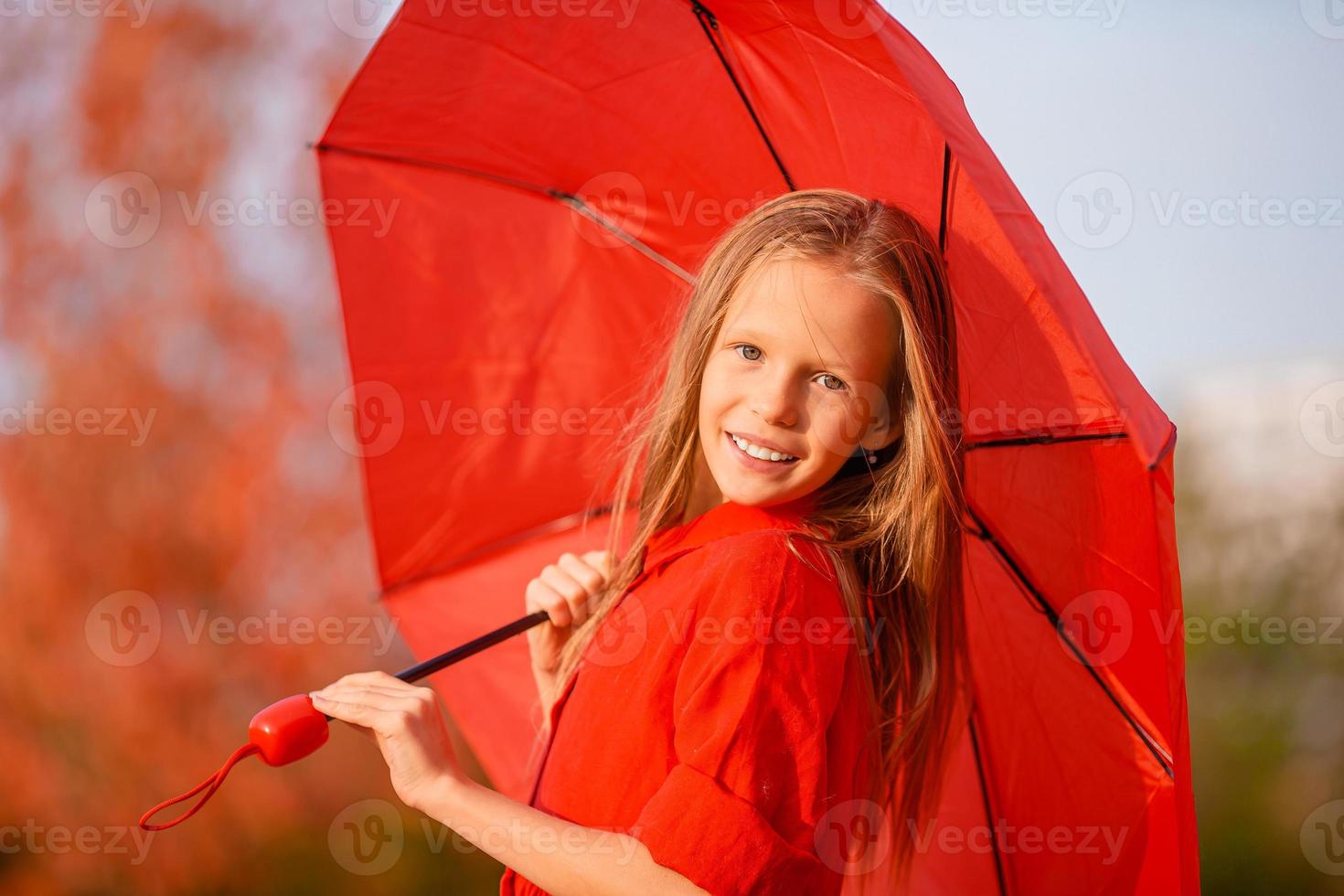 contento bambino ragazza ride sotto rosso ombrello foto