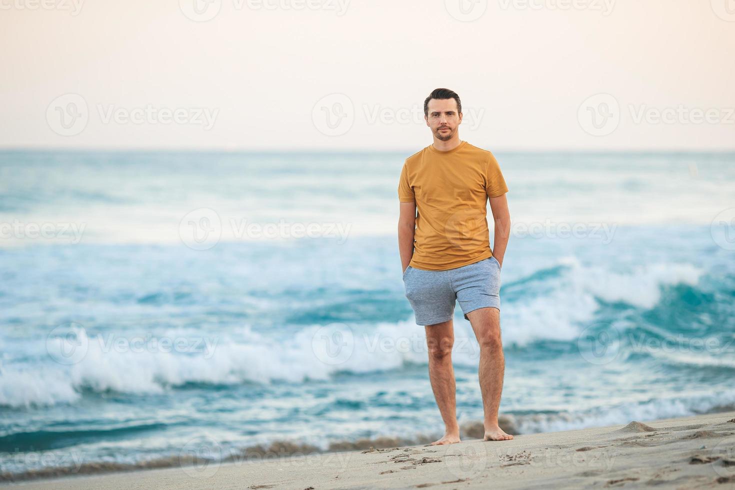 giovane uomo a piedi su il spiaggia a tramonto foto