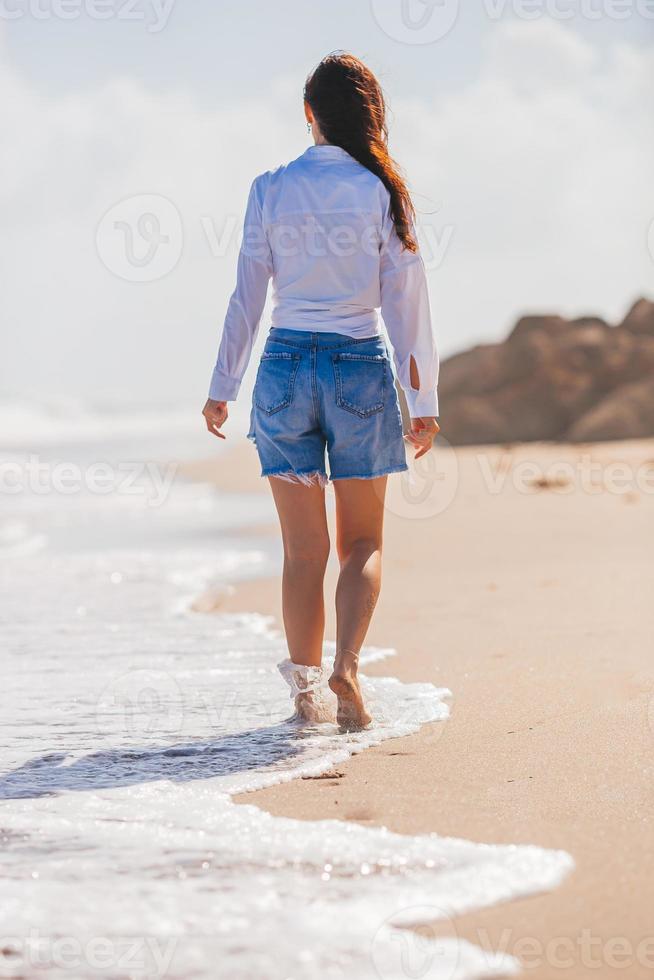 giovane contento donna a piedi su il spiaggia foto