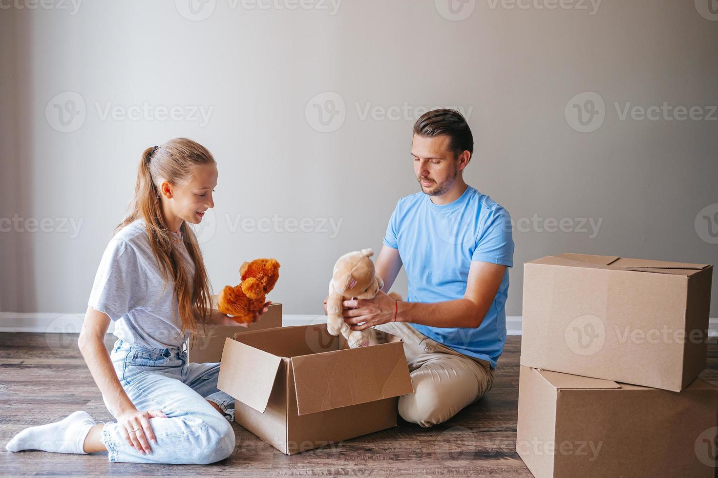 famiglia di papà e il suo adolescente ragazza avere divertimento nel loro nuovo casa con cartone scatole. famiglia godere loro in movimento giorno foto