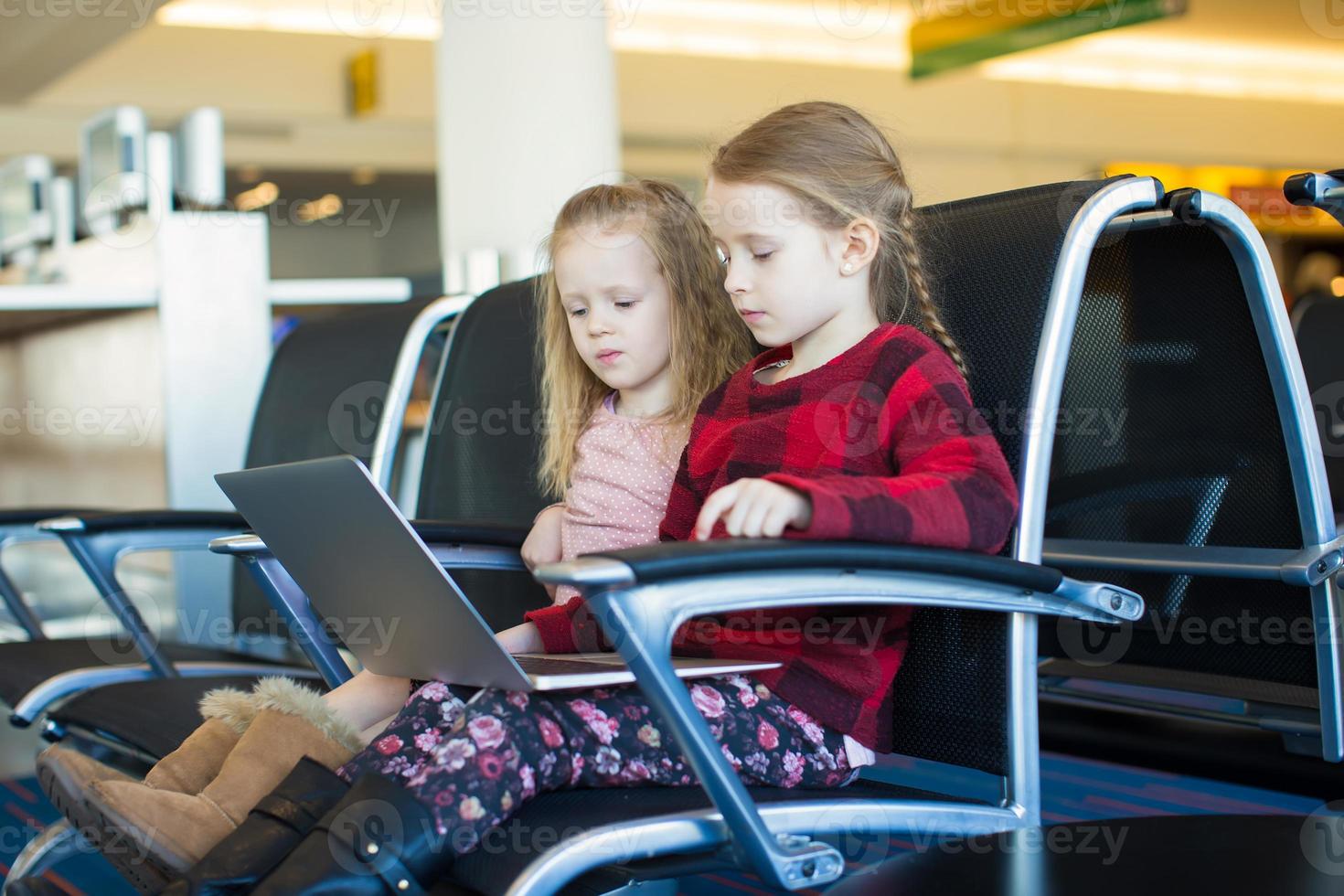 bambini con un' il computer portatile a il aeroporto mentre in attesa il suo volo foto