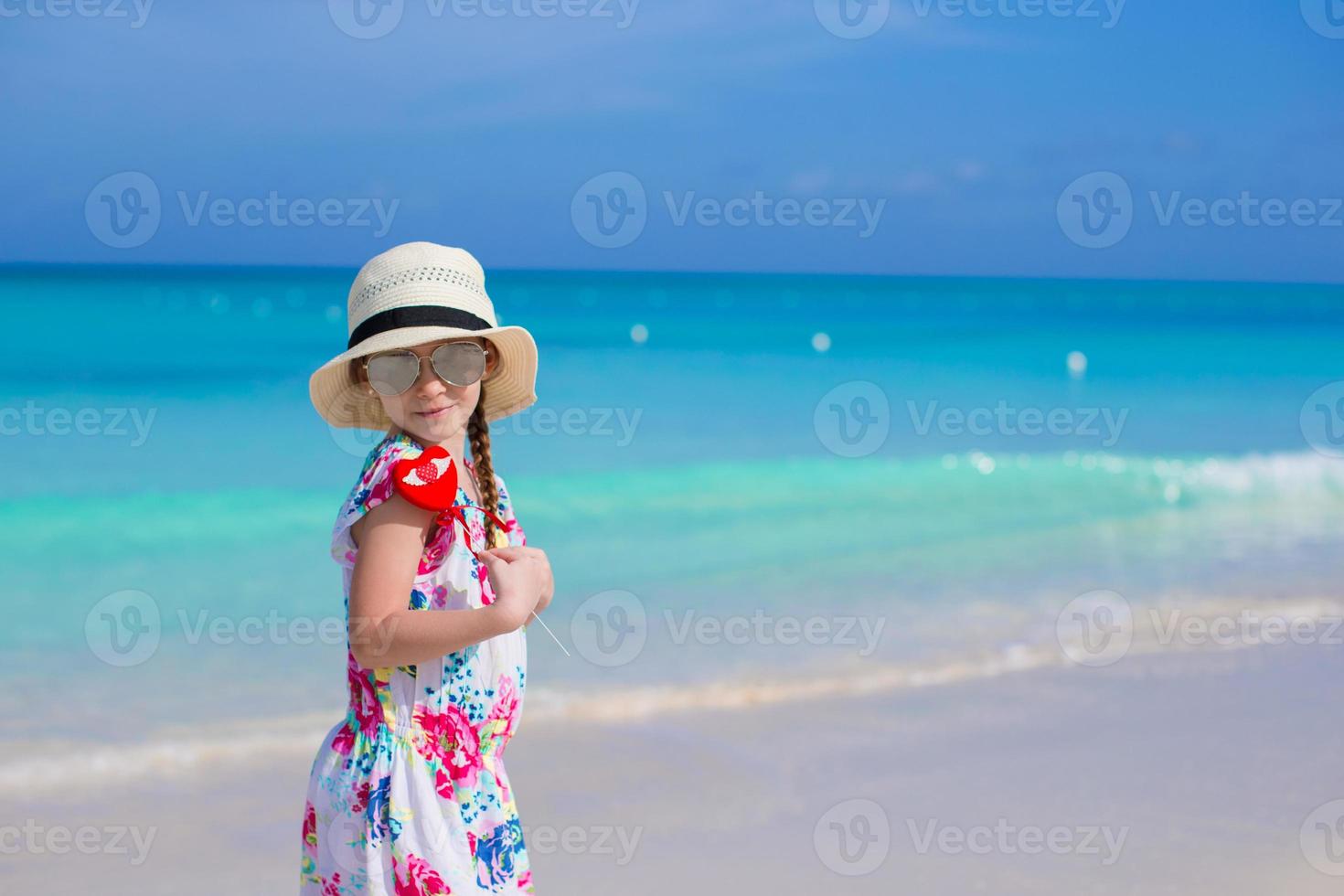 poco contento ragazza con rosso cuore nel mani su un' tropicale spiaggia foto