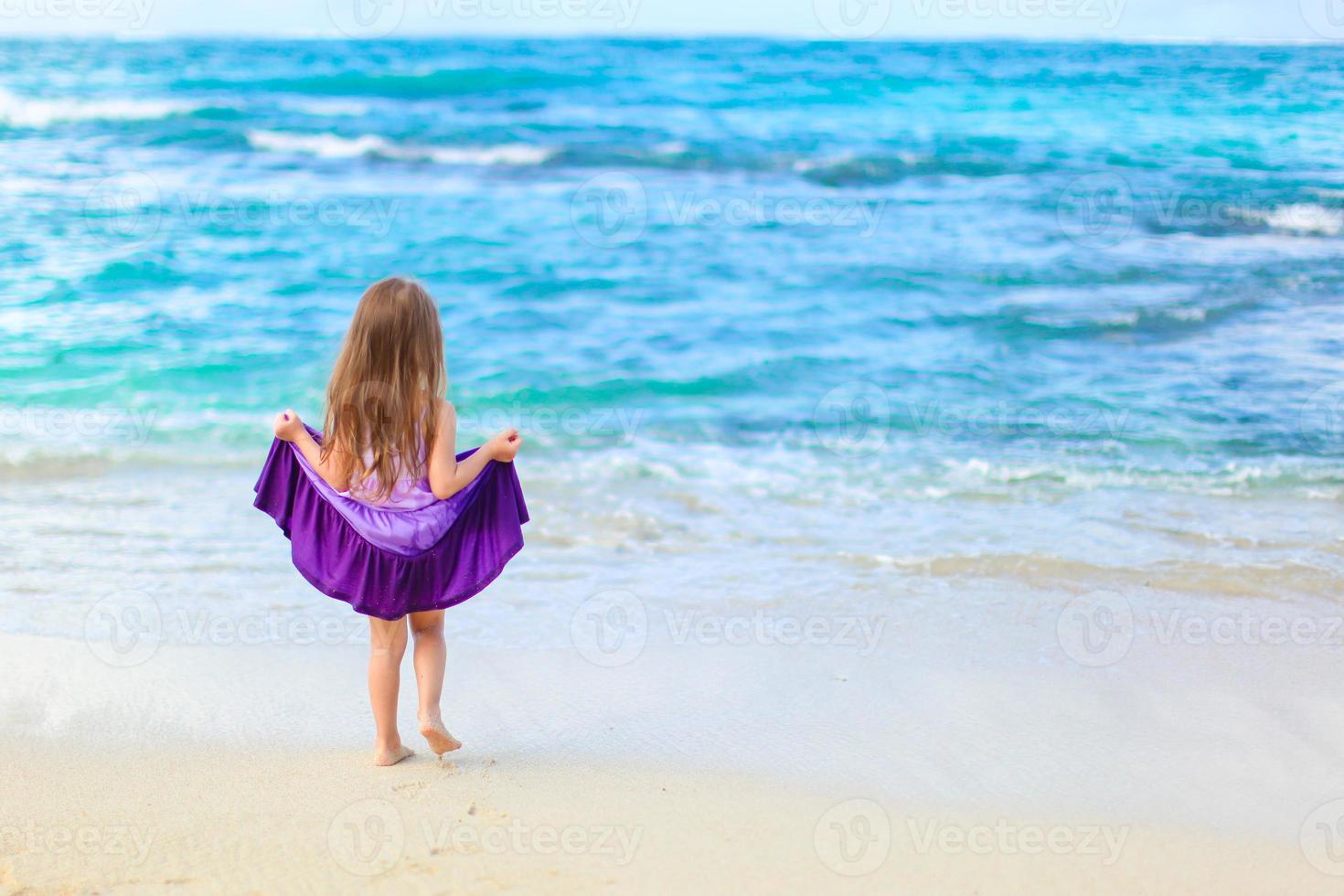 poco ragazza avendo divertimento su tropicale spiaggia con turchese oceano acqua foto