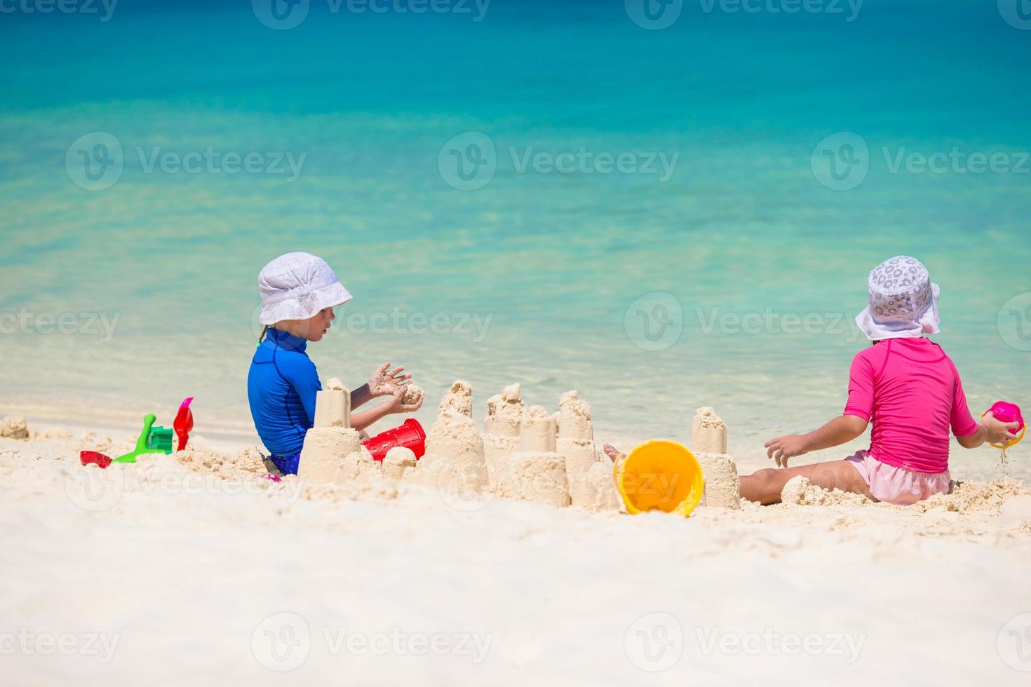 Due bambini fabbricazione sabbia castello e giocando a tropicale spiaggia foto