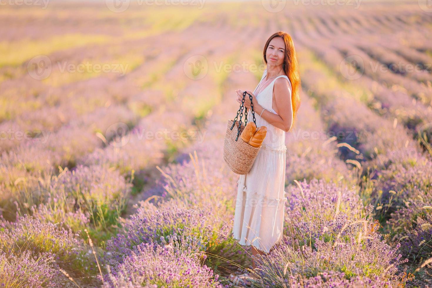 donna nel lavanda fiori campo a tramonto nel bianca vestito e cappello foto