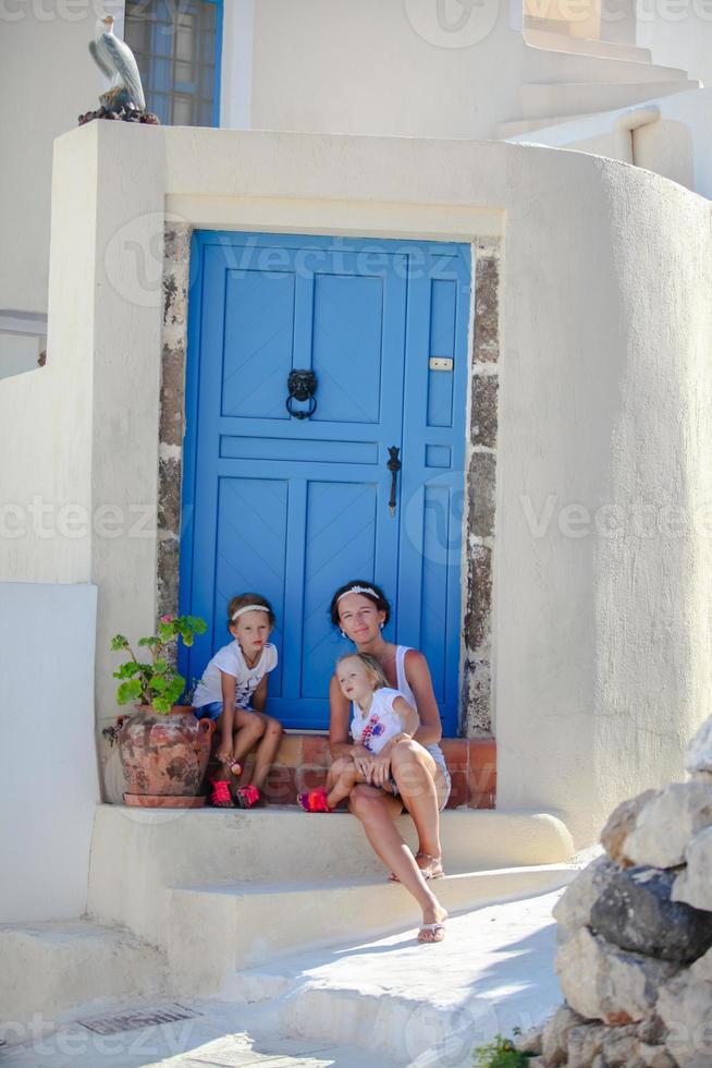 giovane madre e sua figlia seduta su gradino della porta vecchio Casa strada emporio, santorini foto