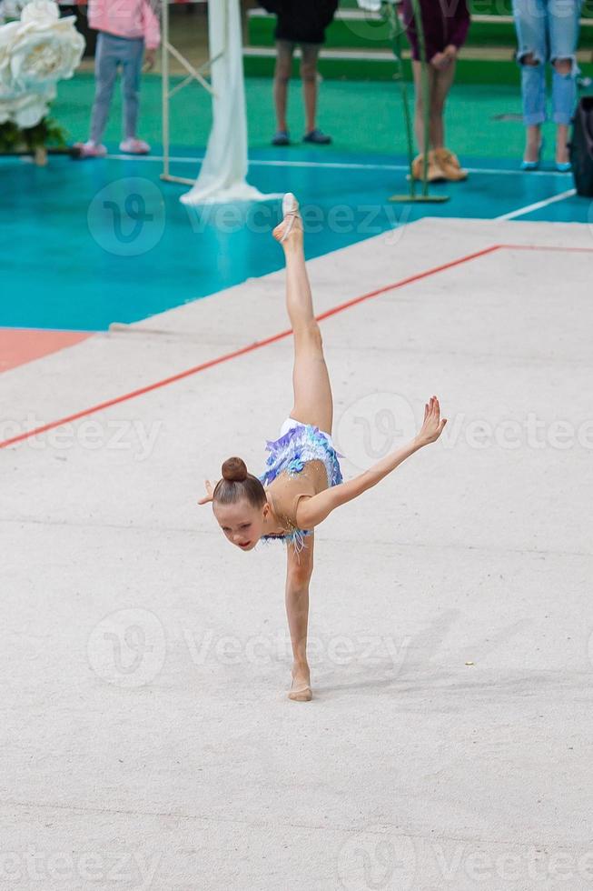 bellissimo poco attivo ginnasta ragazza con sua prestazione su il tappeto foto