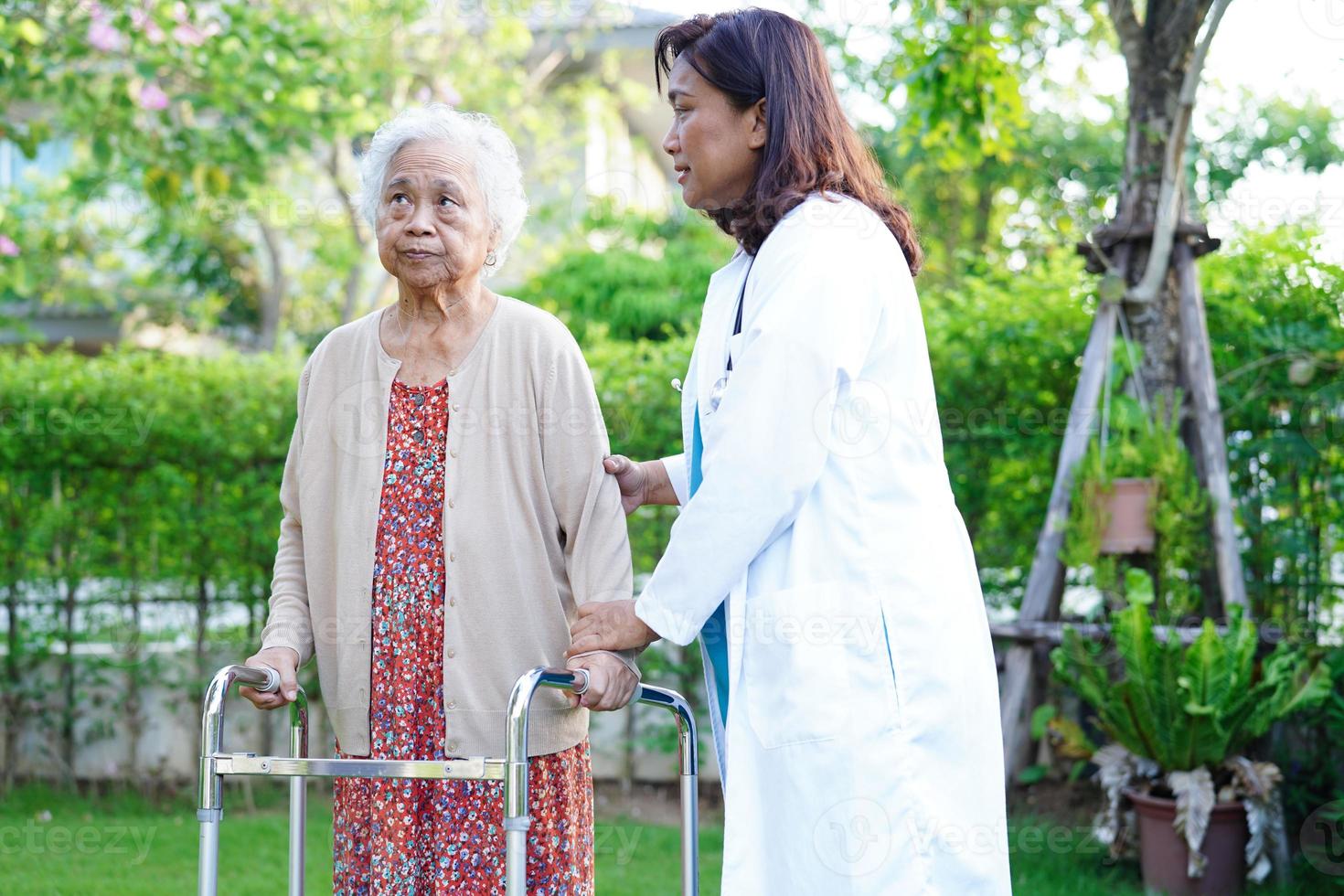 camminata del paziente di disabilità della donna anziana asiatica con il deambulatore nel parco, concetto medico. foto
