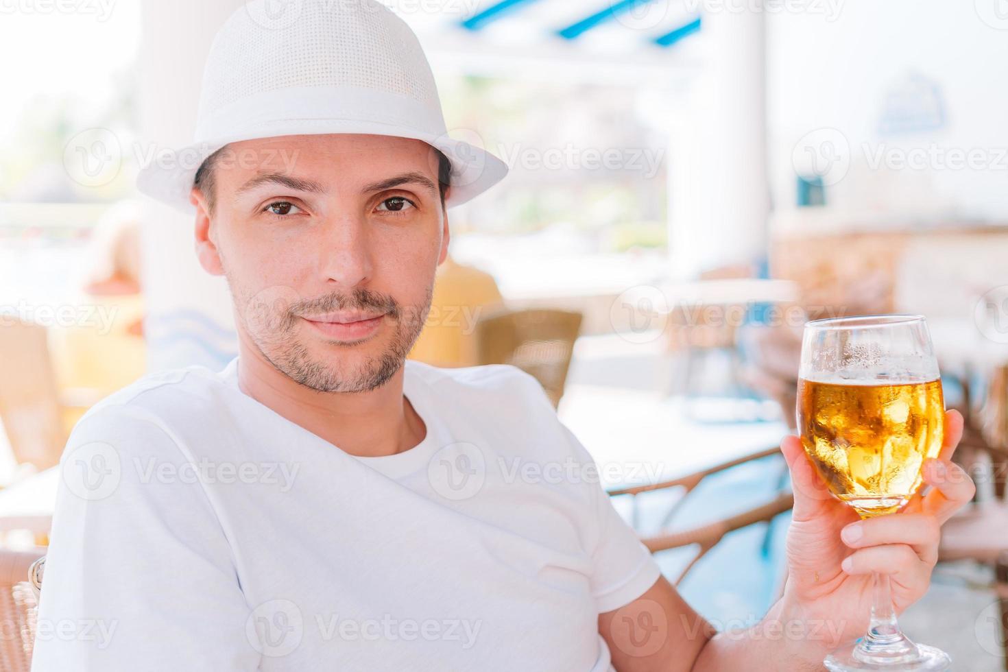 giovane uomo con birra su il spiaggia nel all'aperto bar foto