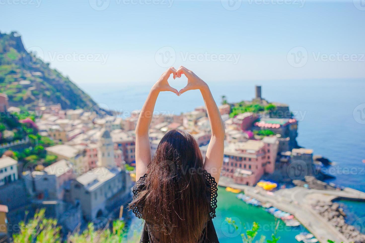 bellissimo ragazza fabbricazione con mani cuore forma su il vecchio costiero cittadina sfondo di vernazza, cinque terre nazionale parco, liguria, Italia ,Europa foto