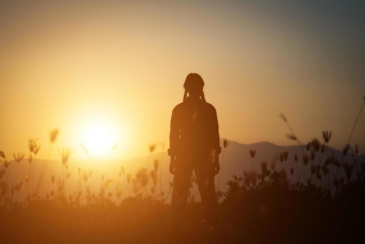 silhouette di una donna che prega su uno sfondo di bel cielo foto