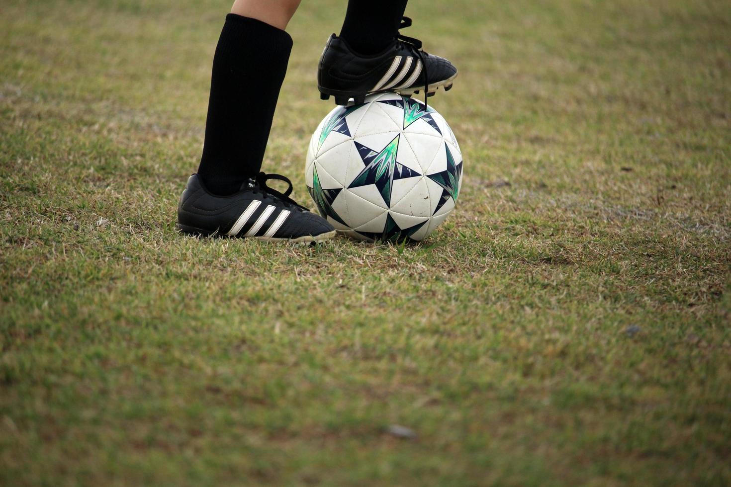 piede di bambino sul pallone da calcio foto