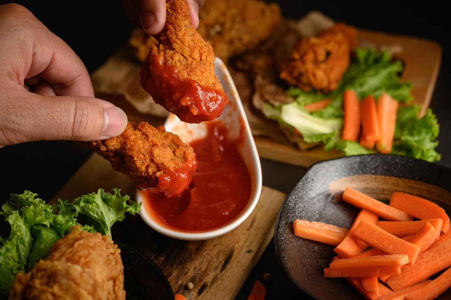 mano che immerge il pollo fritto croccante nella salsa foto