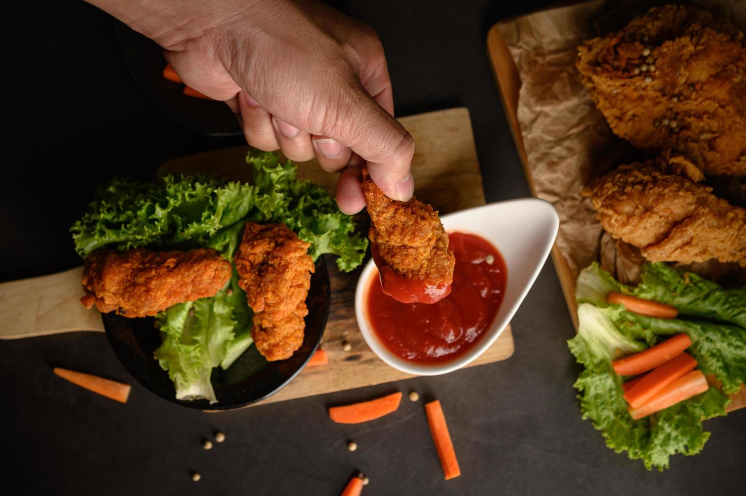 mano che immerge il pollo fritto croccante nella salsa foto