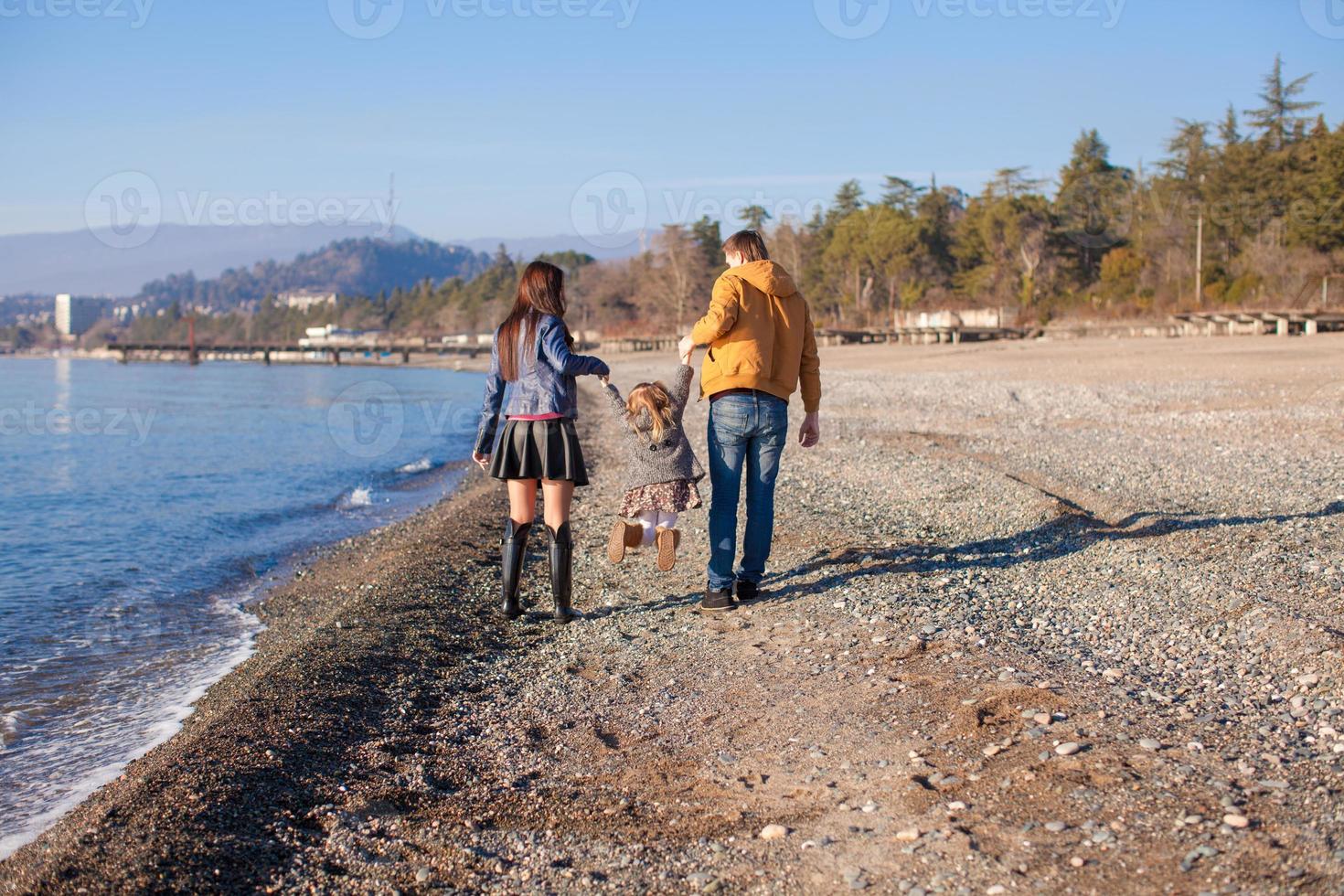 famiglia di tre vicino il nero mare nel inverno soleggiato giorno foto