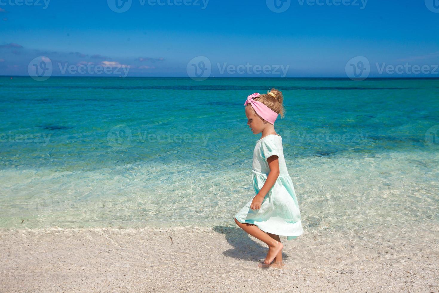 carino poco ragazza giocando nel superficiale acqua a bianca spiaggia foto