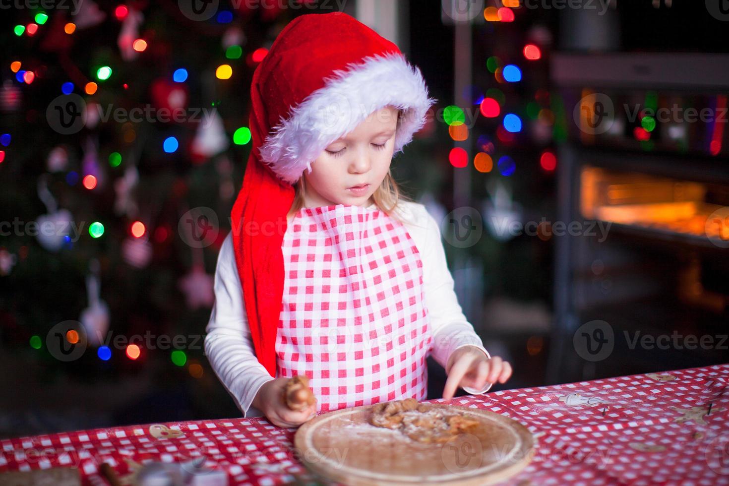 adorabile bambina che mangia la pasta per i biscotti allo zenzero in cucina foto