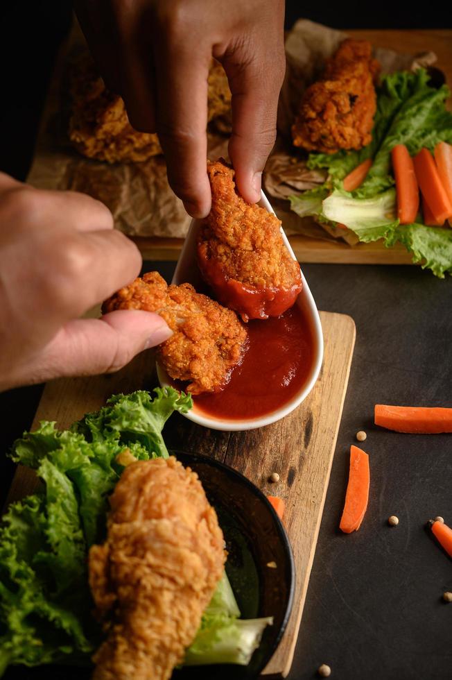 due mani che tengono le offerte di pollo croccanti in salsa di pomodoro foto