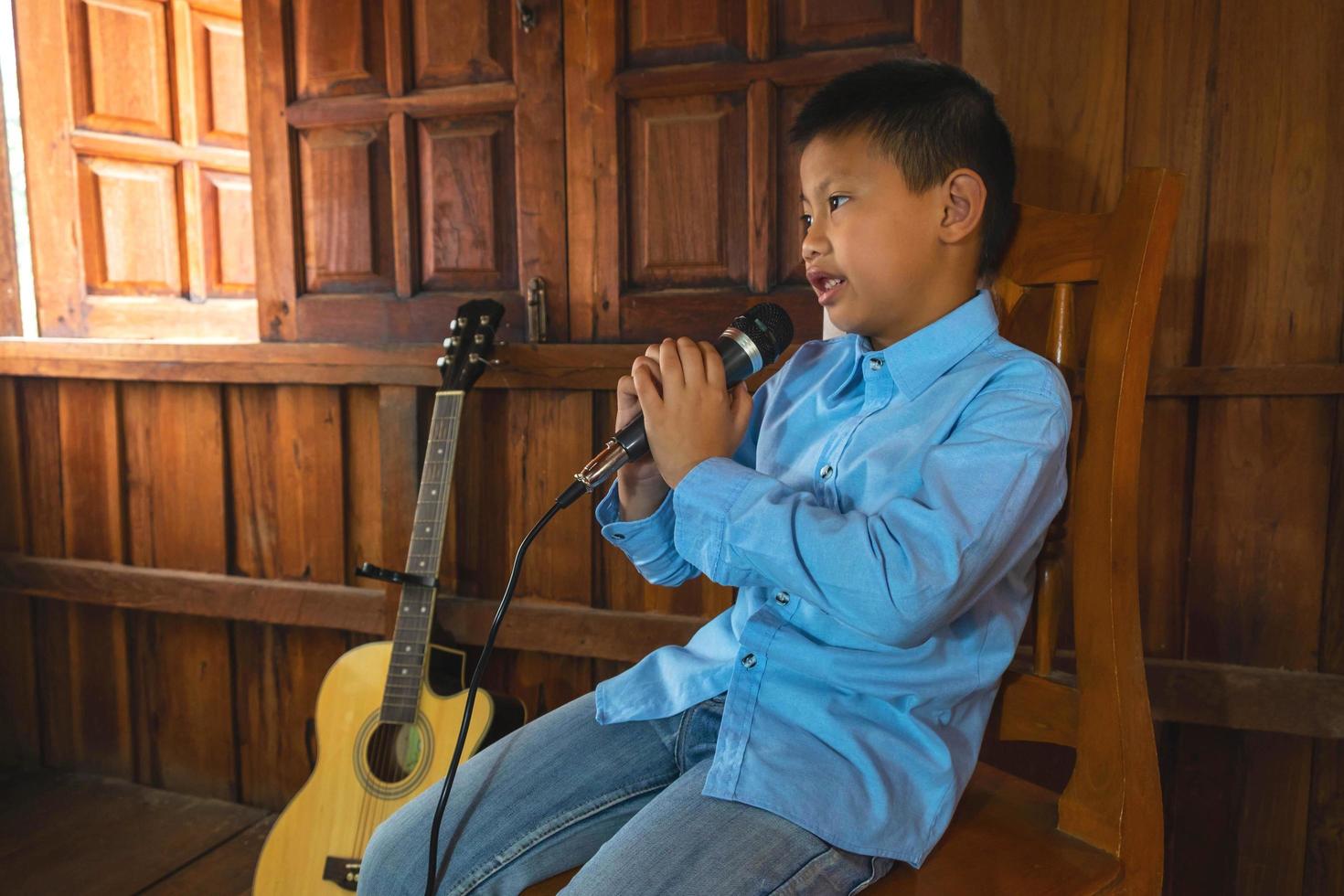 ragazzo che canta accanto a una chitarra foto