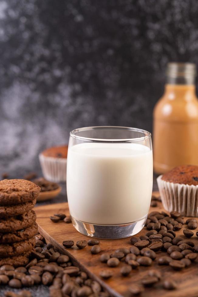 latte in un bicchiere con chicchi di caffè e muffin foto