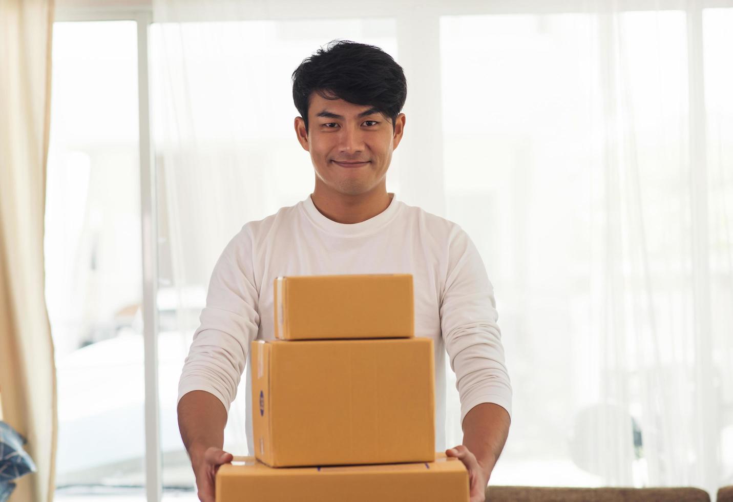 giovane uomo di consegna logistica sorridente che tiene le scatole foto