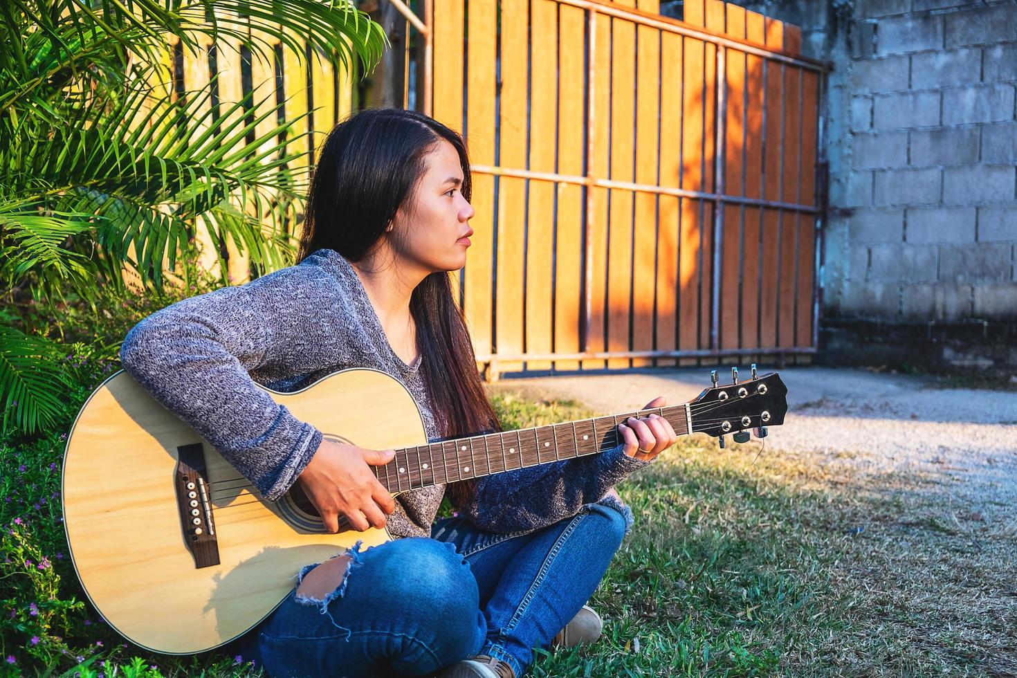 donna seduta fuori a suonare una chitarra foto