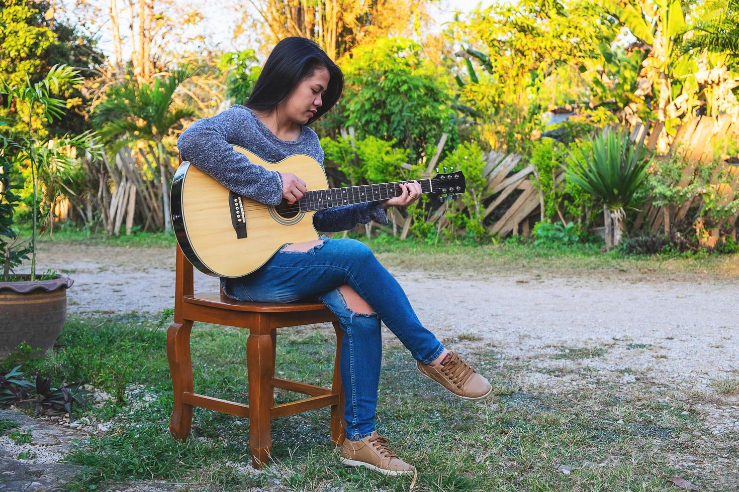 donna seduta su una sedia a suonare una chitarra foto