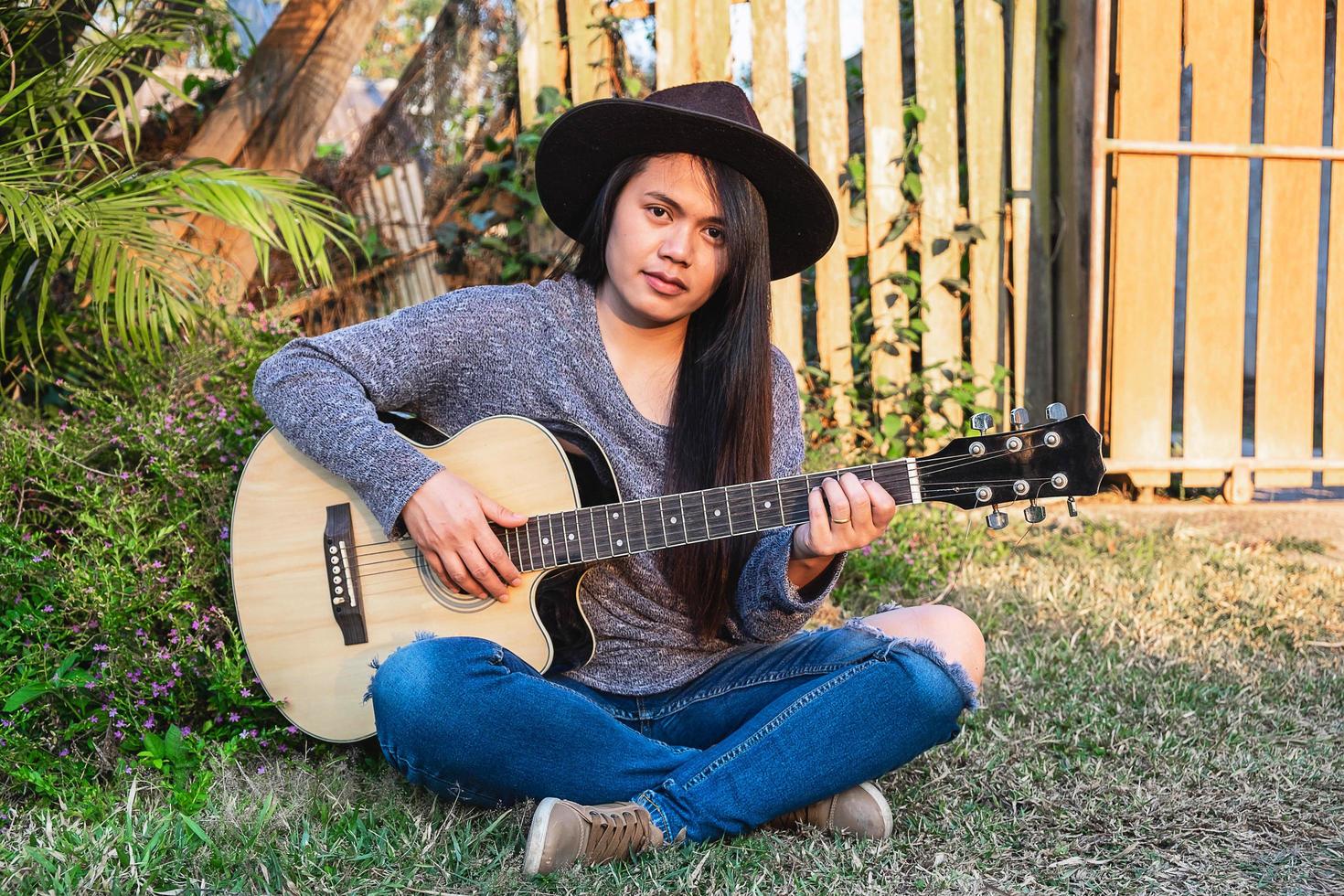 donna che suona una chitarra in un giardino foto
