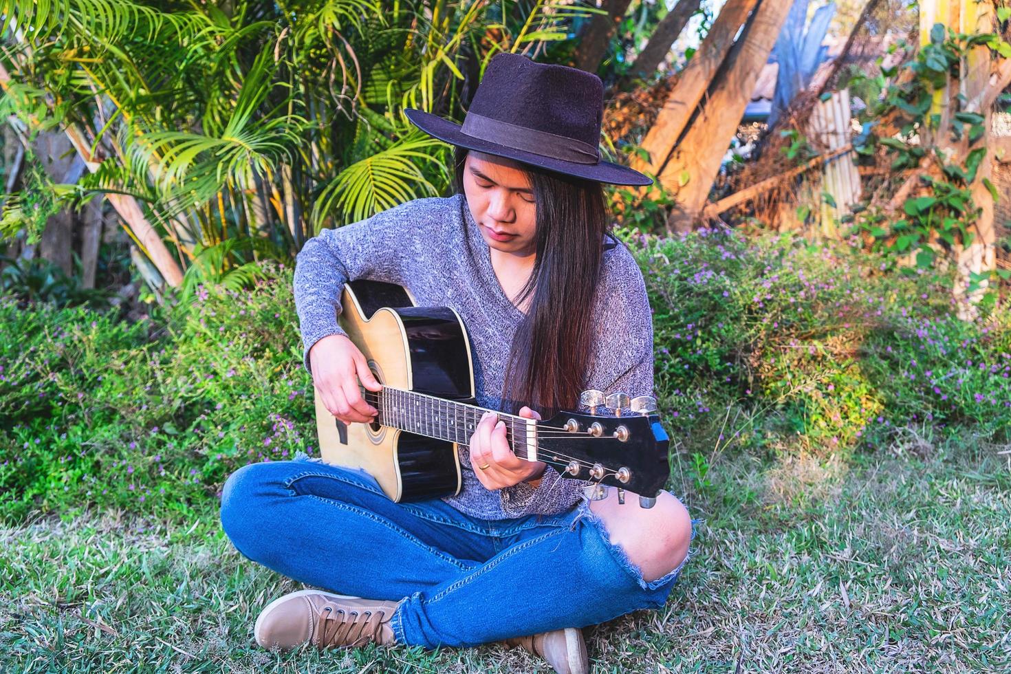 donna in un giardino a suonare la chitarra foto