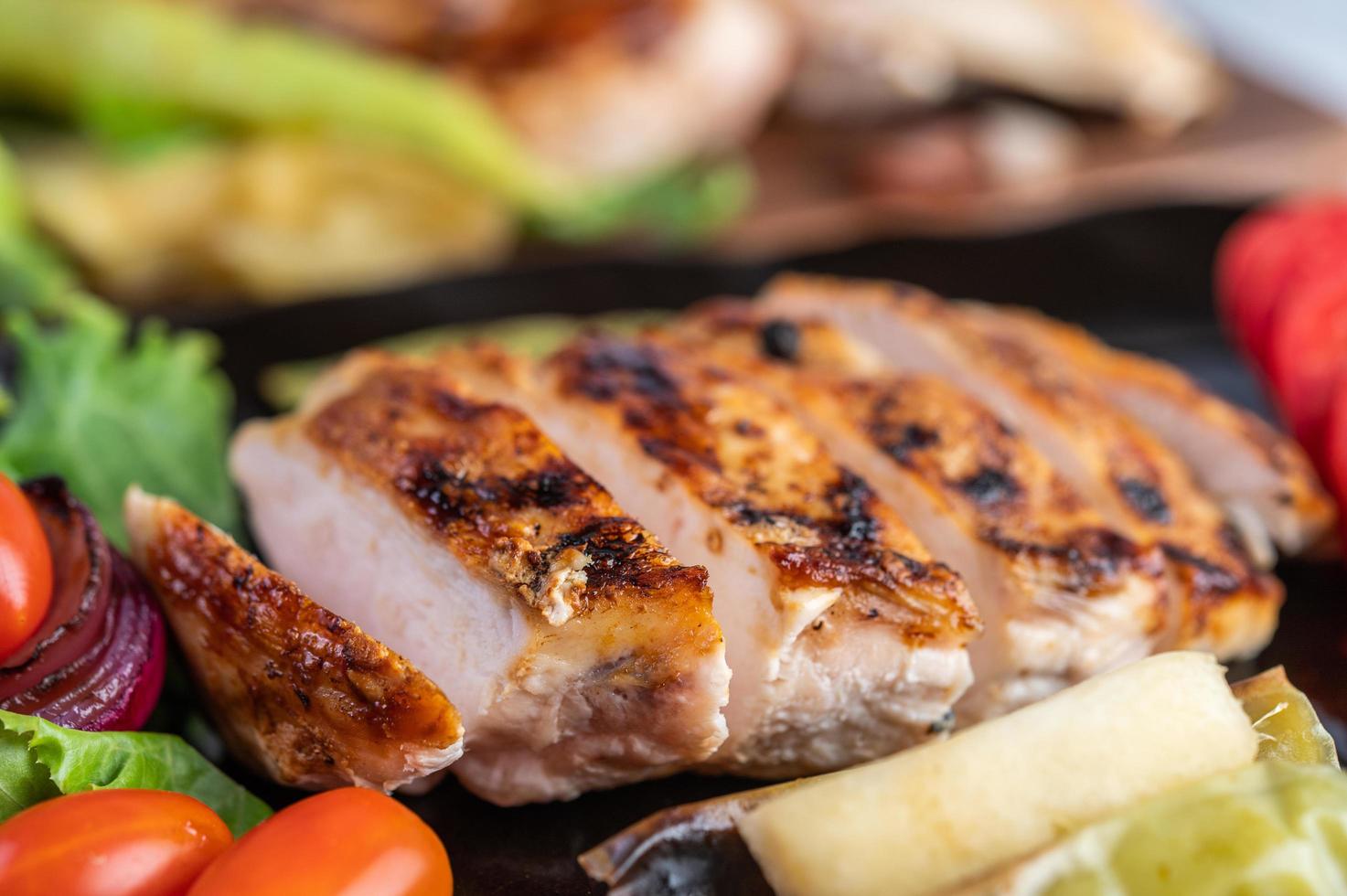 bistecca di pollo con insalata di verdure su un piatto nero foto