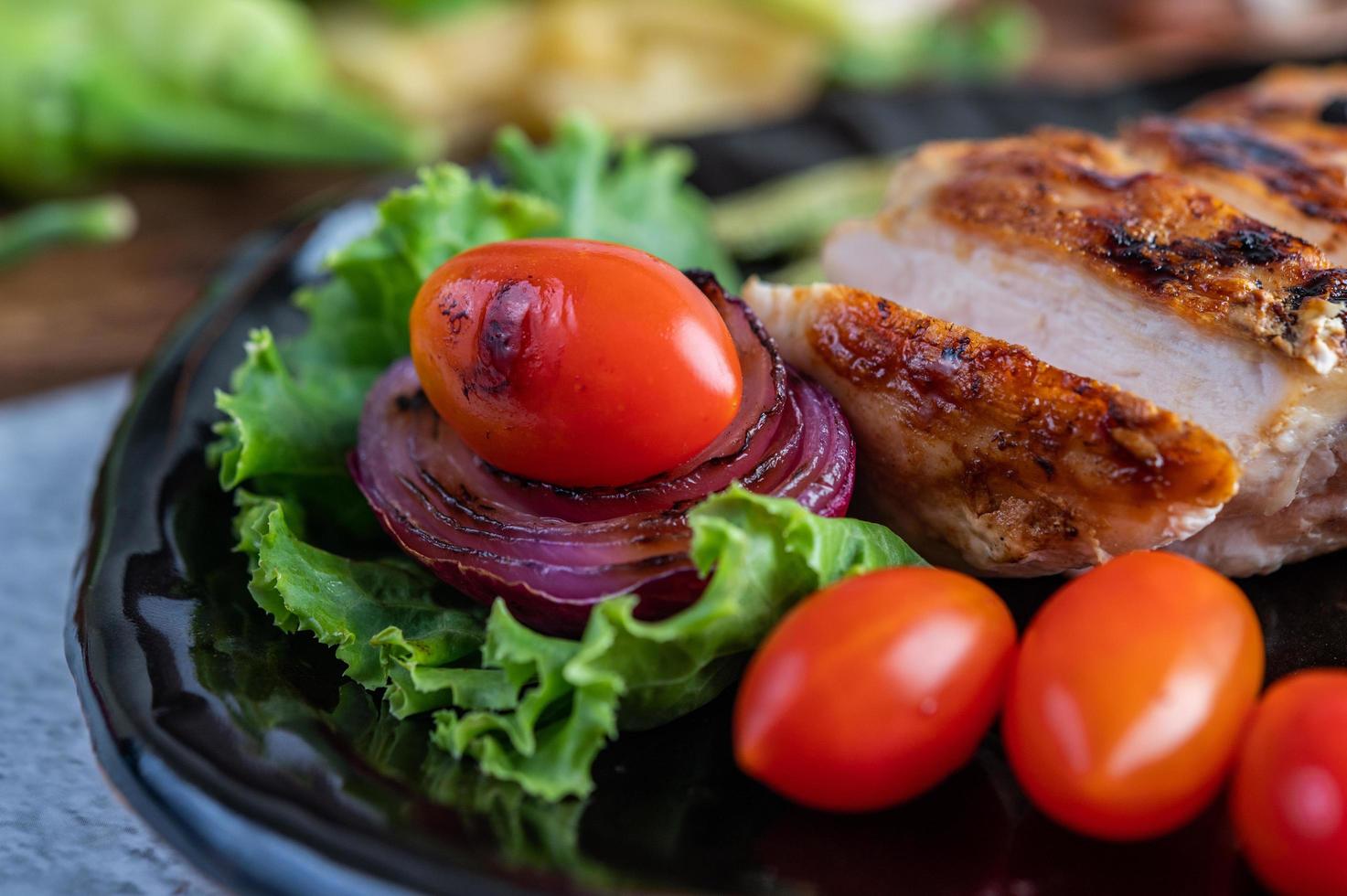 bistecca di pollo con insalata di verdure su un piatto nero foto