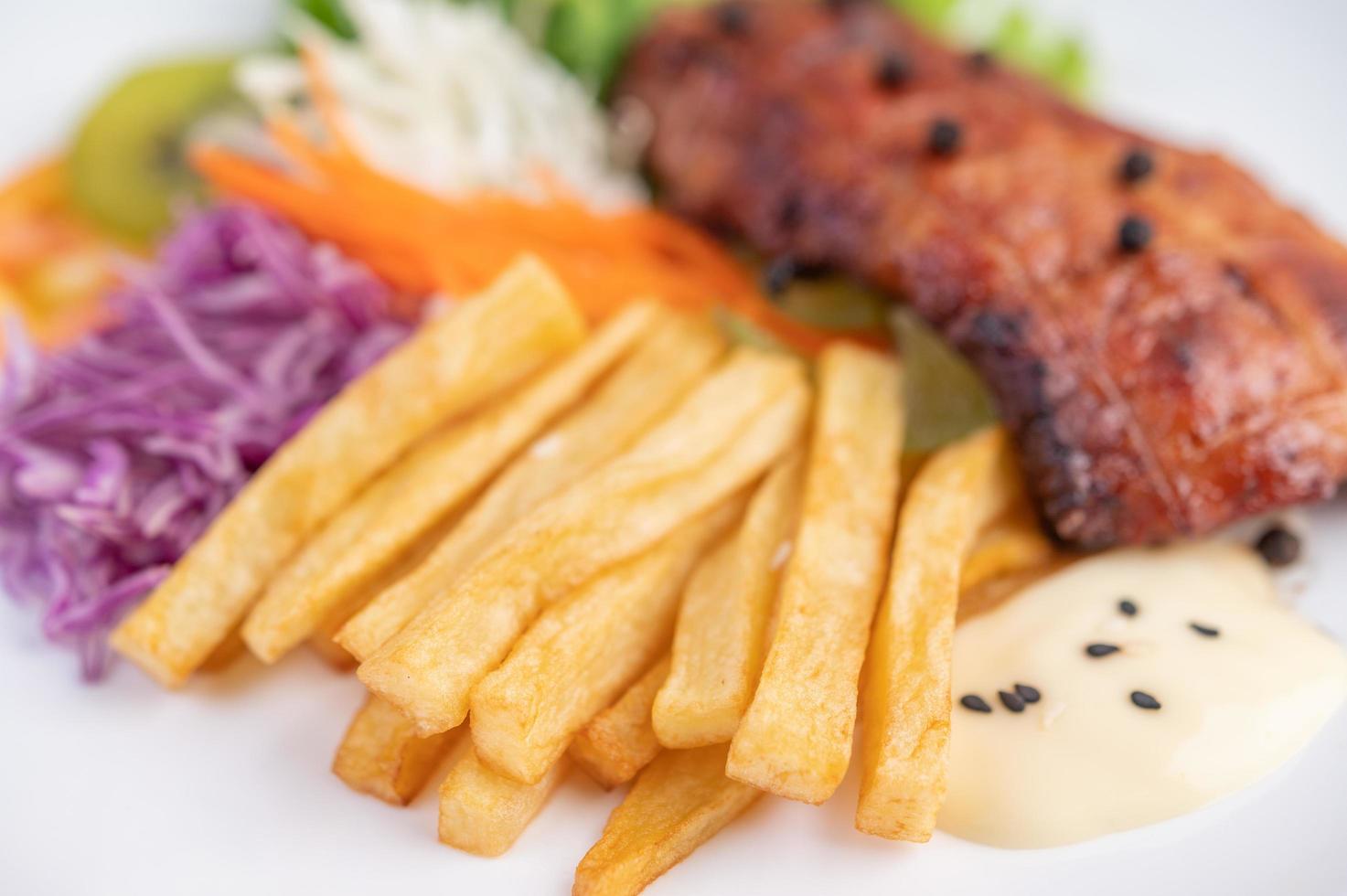 bistecca di pesce con patatine fritte e insalata foto