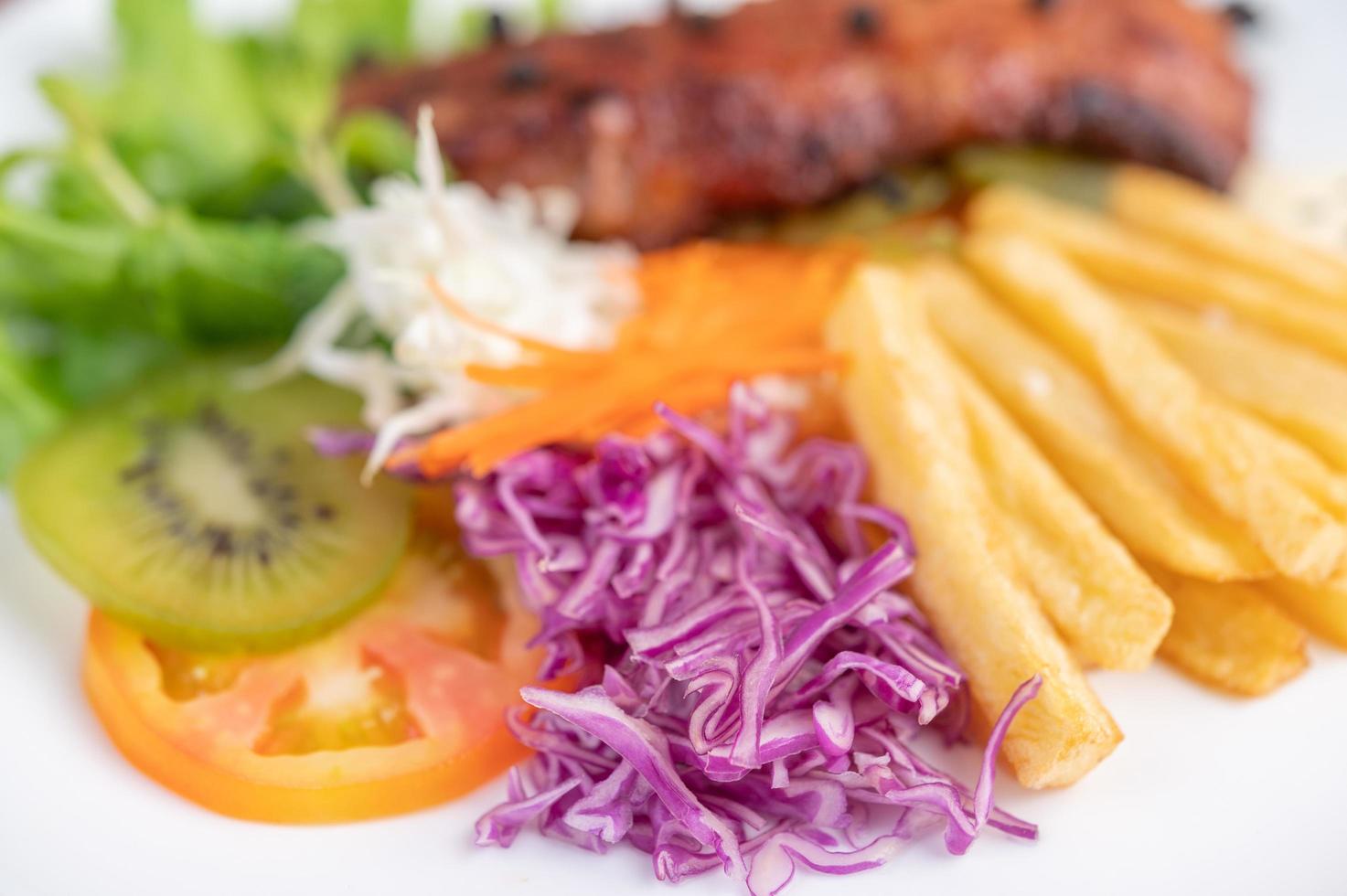 bistecca di pesce con patatine fritte, frutta e verdura foto