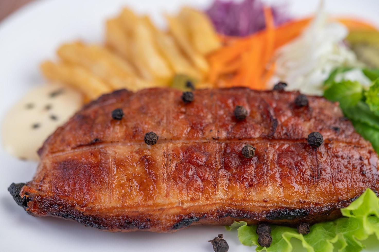 bistecca di pesce con patatine fritte e insalata foto