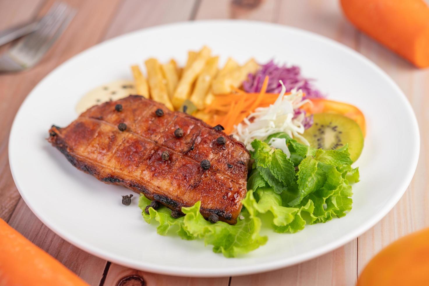 bistecca di pesce con patatine fritte e insalata foto