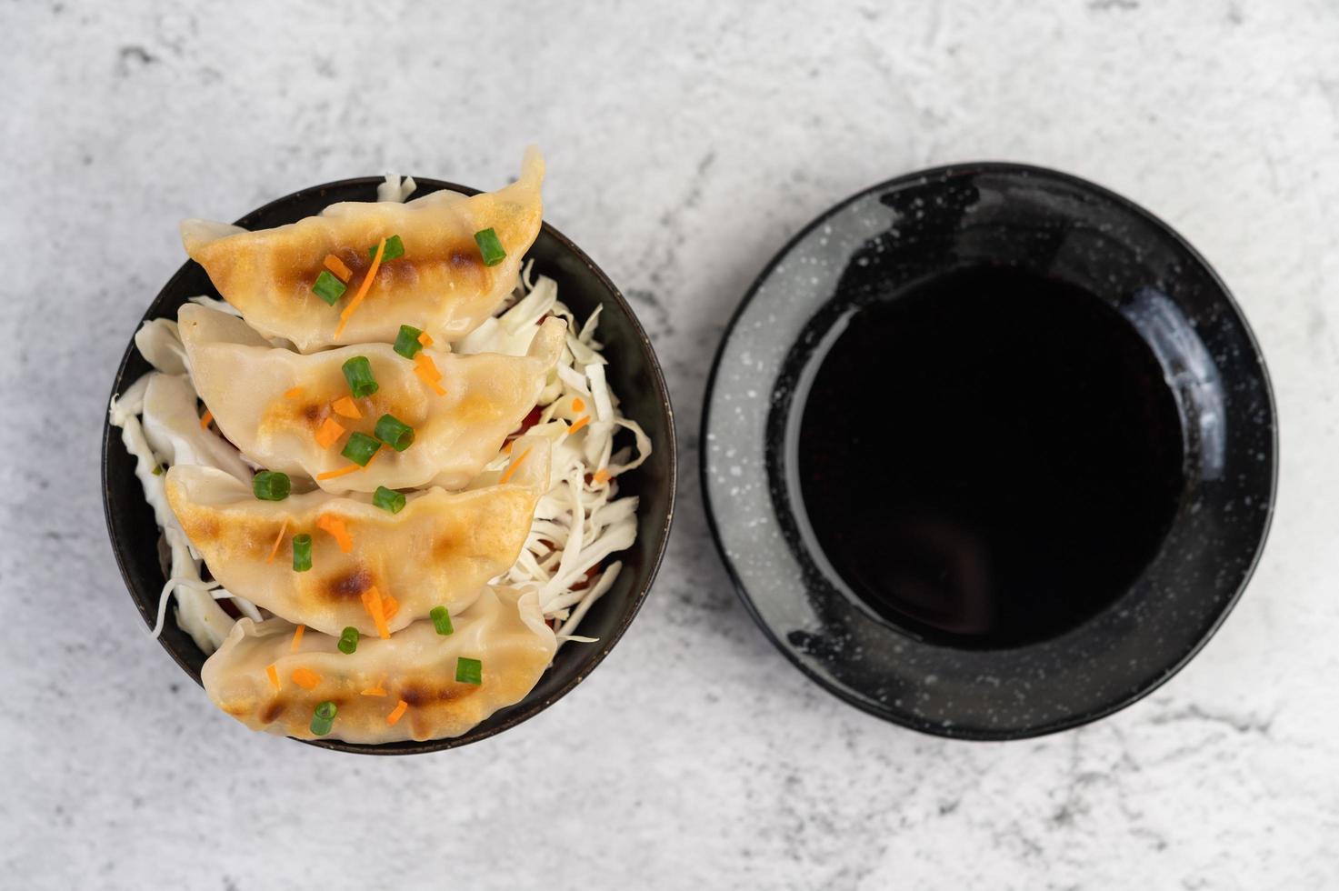 gyoza in una tazza nera con salsa foto