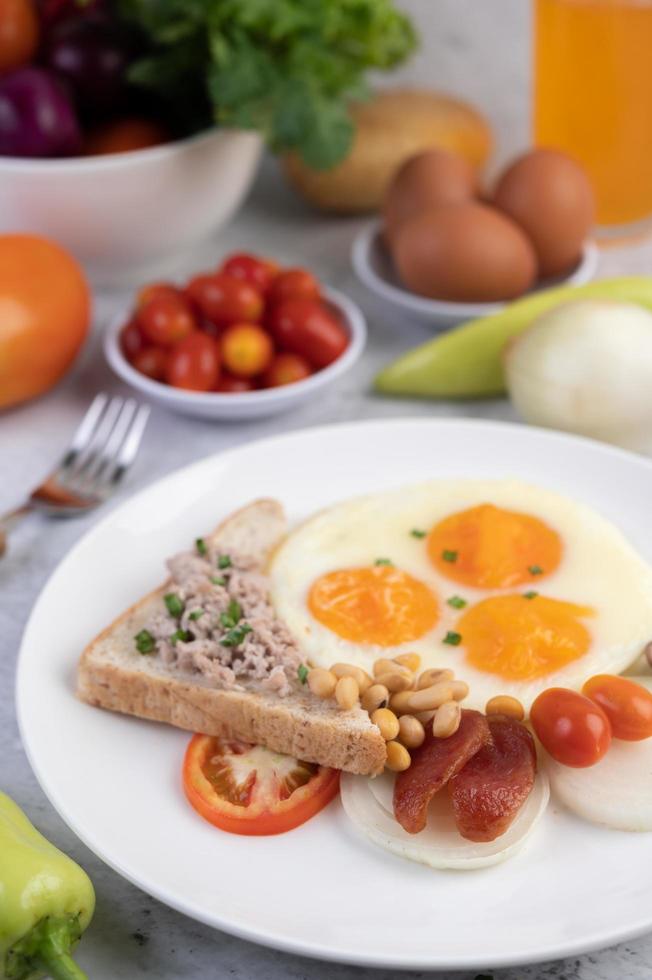 uova fritte, salsiccia, carne di maiale tritata, pane e fagioli rossi foto