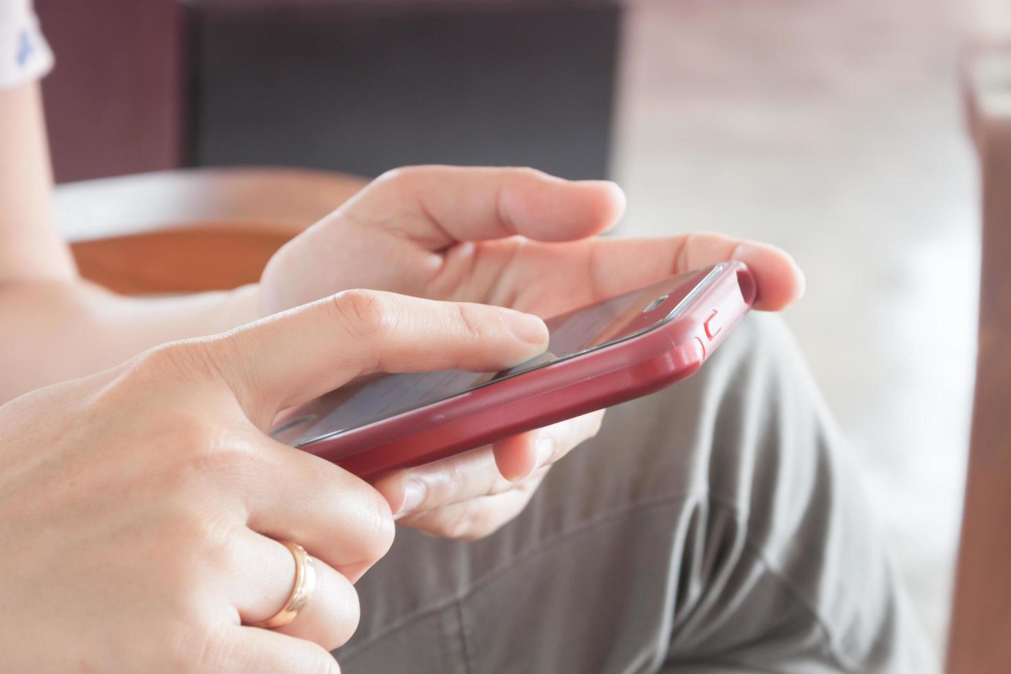 primo piano delle mani che tengono un telefono rosso foto